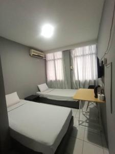 a small room with two beds and a table at Hotel Iramanis in Lahad Datu