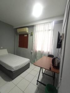 a bedroom with a bed and a desk and a table at Hotel Iramanis in Lahad Datu