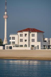 a building with a lighthouse in the background next to the water at Euforia Retreat and Spa in Eforie Nord
