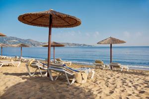 eine Gruppe von Stühlen und Sonnenschirmen am Strand in der Unterkunft TUI Magic Life Candia Maris - Adults Only in Ammoudara