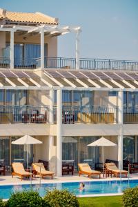 a building with a pool and chairs and umbrellas at TUI Magic Life Candia Maris - Adults Only in Amoudara Herakliou