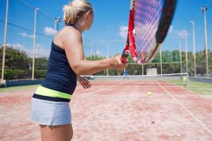 a woman holding a tennis racket on a tennis court at TUI Magic Life Candia Maris - Adults Only in Amoudara Herakliou