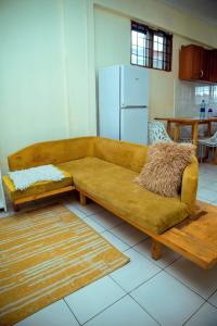 a brown couch sitting in a room with a kitchen at Travellers Home near Mlimani City Mall with free parking in Dar es Salaam