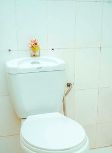 - des toilettes blanches avec un vase de fleurs au-dessus dans l'établissement Travellers Home near Mlimani City Mall with free parking, à Dar es Salaam