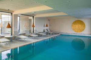a pool in a hotel with chairs and tables at Euforia Retreat and Spa in Eforie Nord