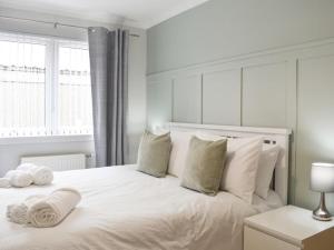 a white bedroom with a large white bed with pillows at Cathwill - Cosy 4 Star Cottage - Cairngorm National Park in Newtonmore