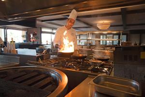 a chef standing in a kitchen preparing food at TUI Magic Life Candia Maris - Adults Only in Amoudara Herakliou