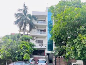 un edificio blanco alto con coches estacionados frente a él en Comfort stay Noida sector 19 en Noida