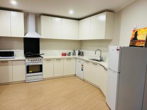 a kitchen with white cabinets and a white refrigerator at Modern Comfy 3 Bedrooms House in Chartwell in Hamilton