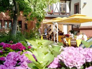 einen Garten mit Tischen, Sonnenschirmen und rosa Blumen in der Unterkunft Hotel Villa Monte Vino in Potsdam