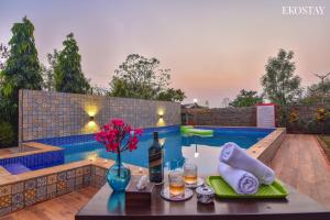 a table with a bottle of wine and a vase of flowers at EKOSTAY- Nest Villa in Karjat
