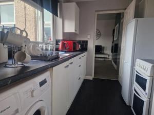 a kitchen with white cabinets and a white refrigerator at Primos Place - 2 Bedroom in Ashington in Ashington