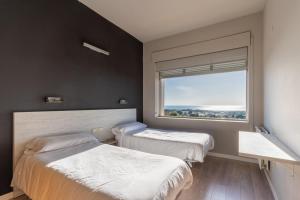 two beds in a room with a large window at Costablanca Explore Hostel Sports & Events in La Marina