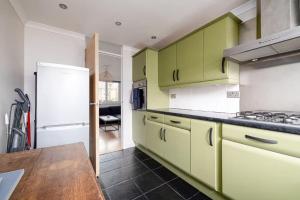 a kitchen with green cabinets and a white refrigerator at GuestReady - Cosy nest with balcony in London in London