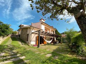 una pequeña casa blanca con una hamaca al aire libre en Olival House, en Paço de Sousa