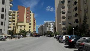 eine Stadtstraße mit geparkten Autos und hohen Gebäuden in der Unterkunft NAFISSA RESIDENCE in La Marsa