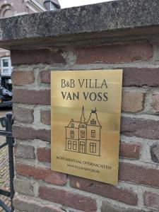 a sign on a brick wall with a building at B&B Villa van Voss in Etten-Leur