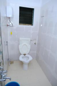 a white bathroom with a toilet and a window at Aashray Guestroom 