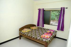 a bed in a room with purple curtains and a window at Aashray Guestroom 
