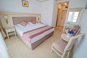 a bedroom with a large bed and a chair at Hotel Sulina International in Mamaia