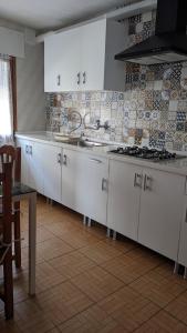 - une cuisine avec des placards blancs et un mur en carrelage dans l'établissement Apartamento Turístico Dalmacia, à Gata