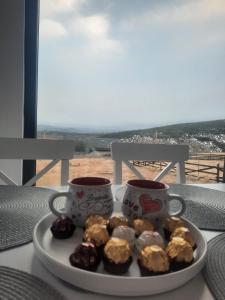 une assiette de beignets assise sur une table avec deux tasses dans l'établissement Tiny House Maguri, à Măguri