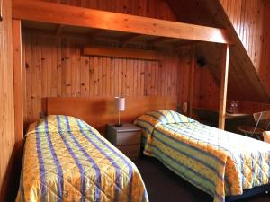 two beds in a room with wooden walls at Logis hôtel & Restaurant - Auberge de la Forêt in Hazebrouck