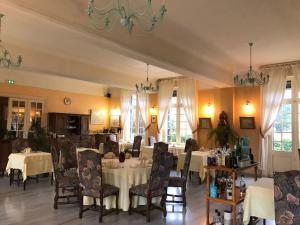 un restaurante con mesas y sillas blancas y ventanas en Logis hôtel & Restaurant - Auberge de la Forêt, en Hazebrouck