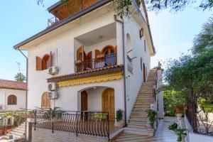 Cette grande maison blanche dispose d'un escalier et d'un balcon. dans l'établissement Villa Cavallaro, à Giardini Naxos