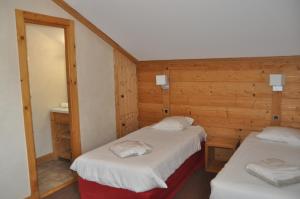 two twin beds in a room with wooden walls at Cortina - 51 - Appart spacieux - 10 pers in Les Deux Alpes