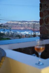 a glass of wine sitting on a table with a view at Anya Suites Santorini in Akrotiri