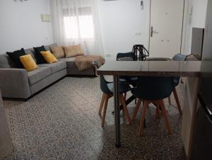 - un salon avec un canapé, une table et des chaises dans l'établissement Gardenia Apartment, à Séville