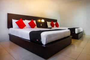 two beds in a room with red and white pillows at Hotel Del Valle, Tecamachalco in Tecamachalco
