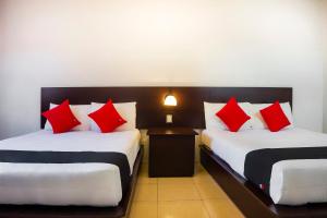 TecamachalcoにあるCapital O Del Valle, Tecamachalcoの赤と白の枕が備わる客室内のベッド2台