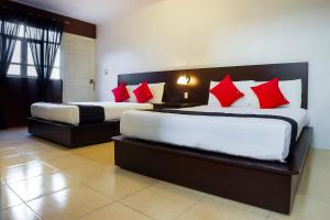 two beds in a room with red and white pillows at Hotel Del Valle, Tecamachalco in Tecamachalco