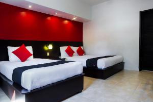 two beds in a hotel room with red walls at Hotel Del Valle, Tecamachalco in Tecamachalco