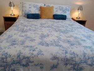 a bed with a blue and white blanket and two lamps at Sunnyside Farm in Grange Over Sands