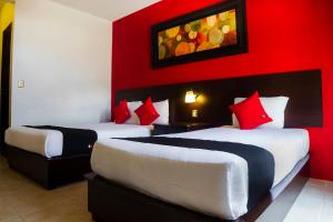 um quarto de hotel com duas camas com paredes vermelhas em Capital O Del Valle, Tecamachalco em Tecamachalco