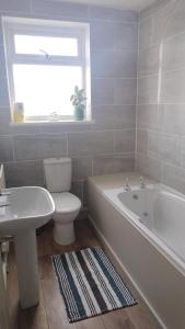 a bathroom with a toilet and a tub and a sink at The Snug in Amlwch