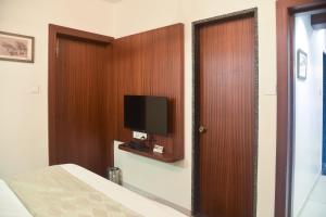 a bedroom with a bed and a tv on a wall at Hotel Old Urban Guest House in Kolhapur