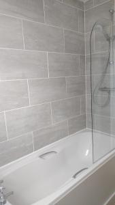 uma banheira branca com uma porta de duche envidraçada em The Snug em Amlwch