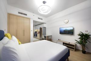 a bedroom with a bed and a tv on the wall at Aura Azizi by Golden Casa in Dubai