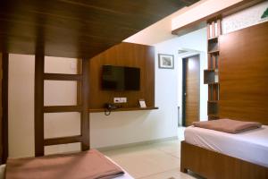 a bedroom with a bed and a flat screen tv at Hotel Old Urban Guest House in Kolhapur