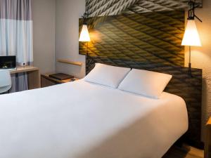 Habitación de hotel con cama blanca grande y 2 almohadas en ibis Bourg en Bresse en Bourg-en-Bresse