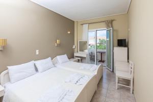 a bedroom with a large white bed and a desk at Hotel Venetia in Perdika