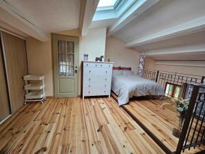 Schlafzimmer mit einem Bett und Holzboden in der Unterkunft Maison au pied des Alpilles - Paradou in Paradou