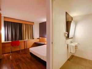 um quarto de hotel com uma cama e uma cadeira vermelha em ibis Rio de Janeiro Barra da Tijuca no Rio de Janeiro