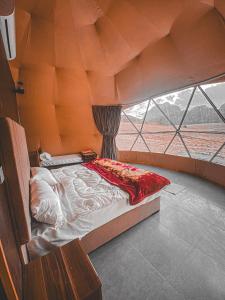 a bed in a room with a large window at Desert Star Luxury Camp in Wadi Rum