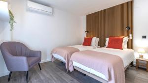 una habitación de hotel con 2 camas y una silla en Amazing 3BDR Duplex in Lisbon by LovelyStay, en Lisboa