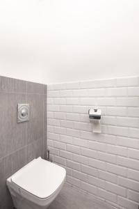a bathroom with a toilet and a white tile wall at Downtown Nature Apartment in Budapest +15 photos